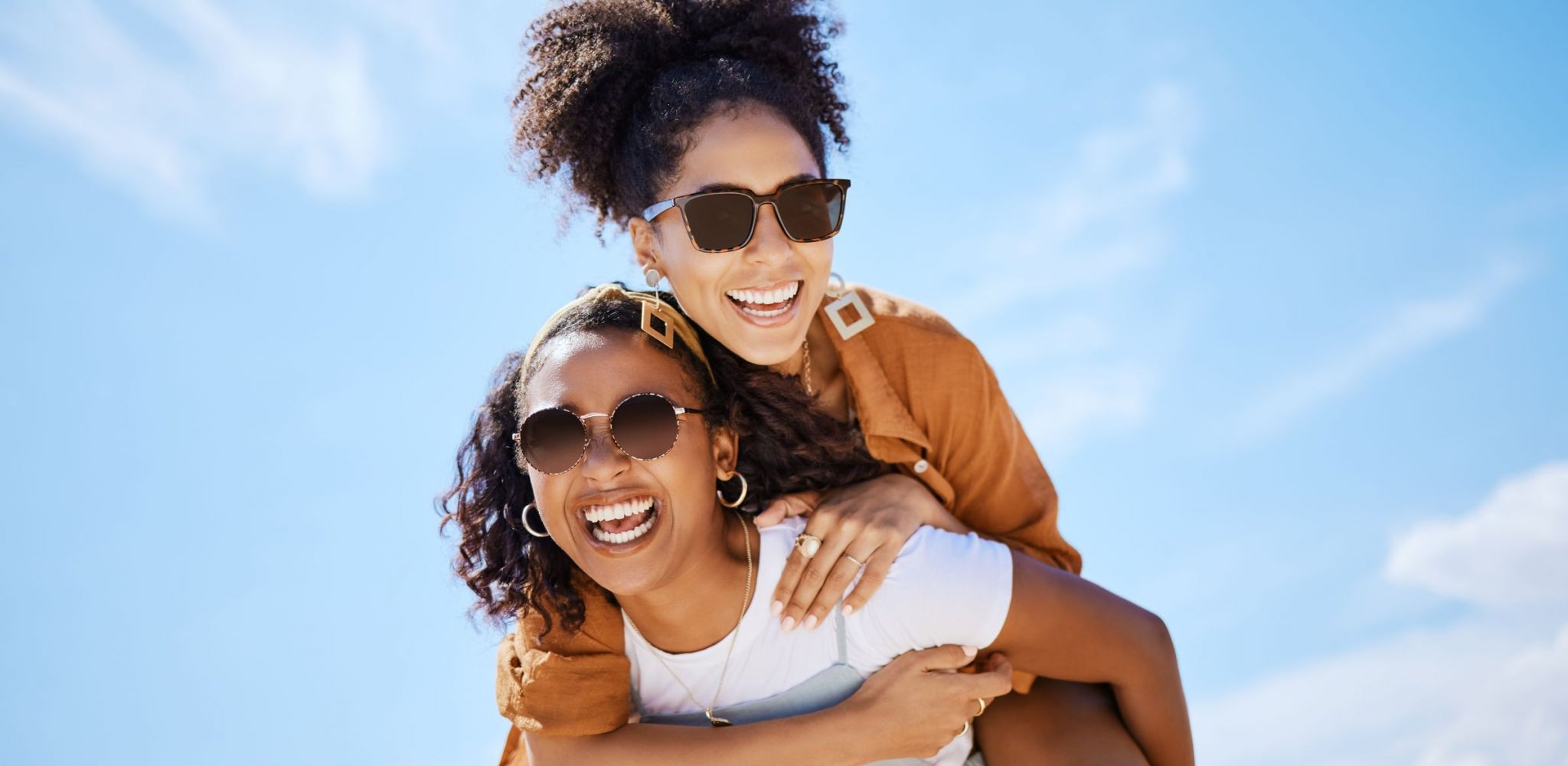 The Austin Apartment HomesThe Austin Apartment Homes Summer, friends and freedom with women and piggy back against the blue sky for hug, lifestyle and happy on Puerto rico holiday. Youth, crazy and friend with girl on vacation with glasses and a smile.