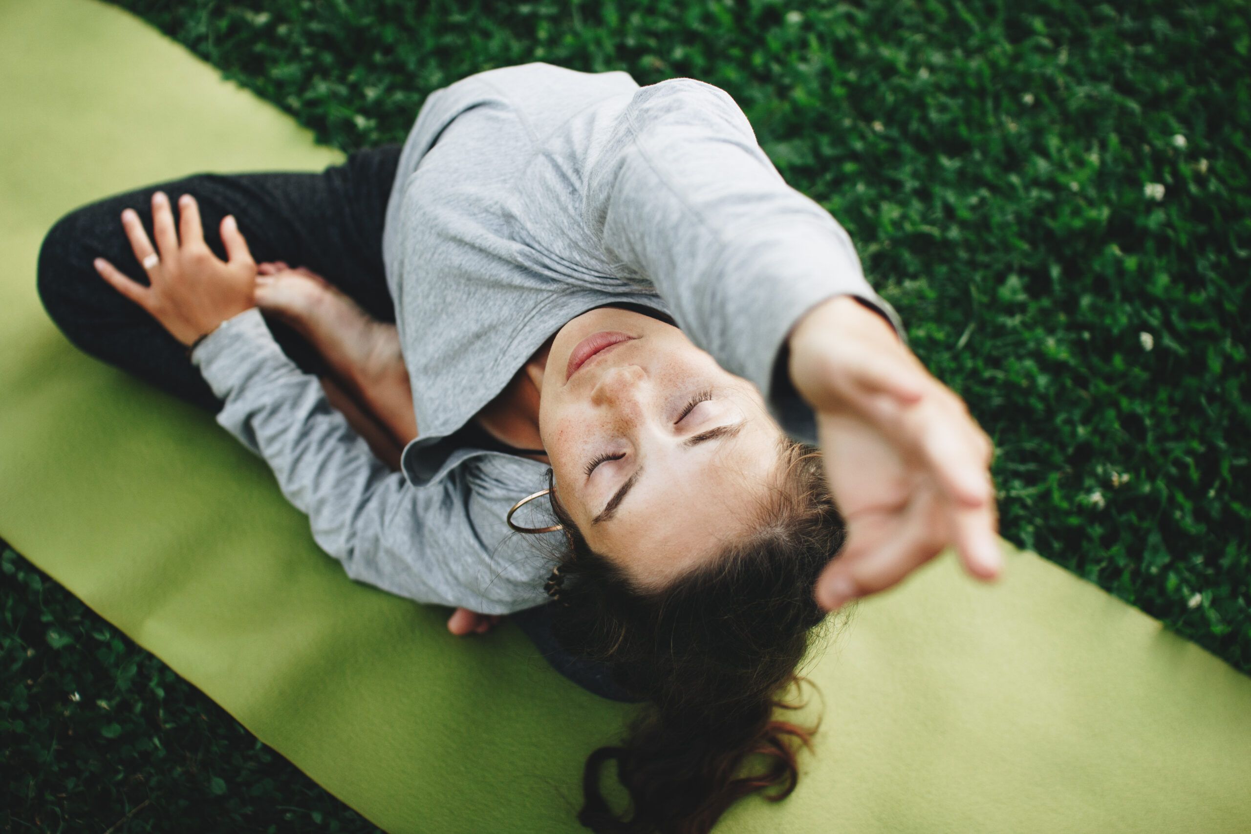 The Austin Apartment Homes Woman is practicing yoga on a green lawn. Young woman relaxes in yoga pose outdoors