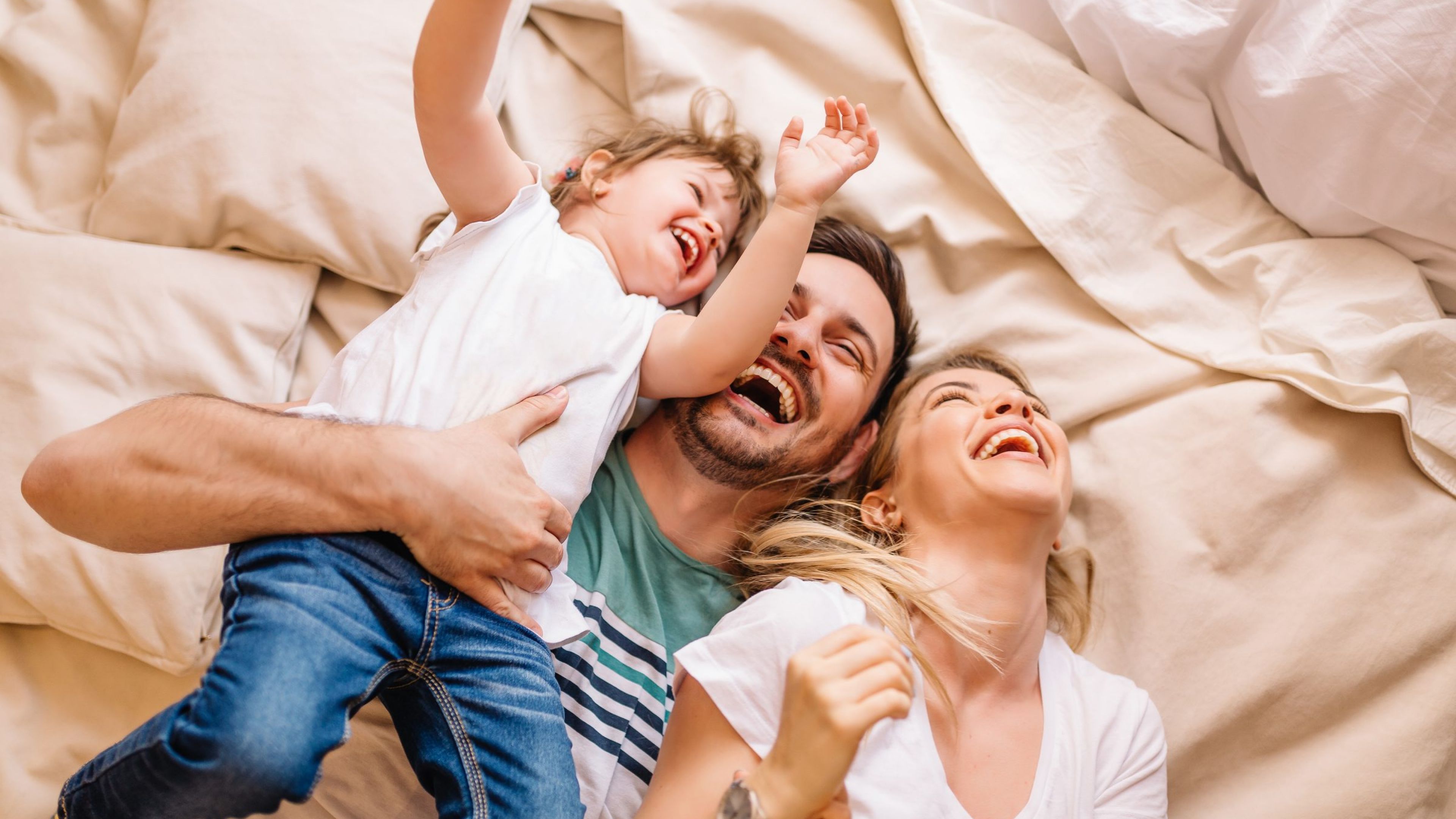 The Austin Apartment HomesThe Austin Apartment Homes Happy family having fun in the bedroom while they lie on bed