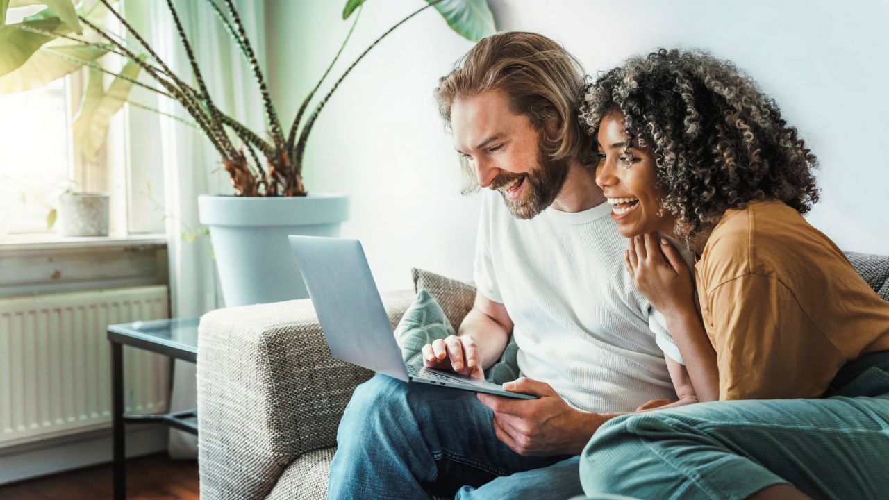 The Austin Apartment Homes 1. A man and woman sit on a couch, focused on a laptop screen between them.